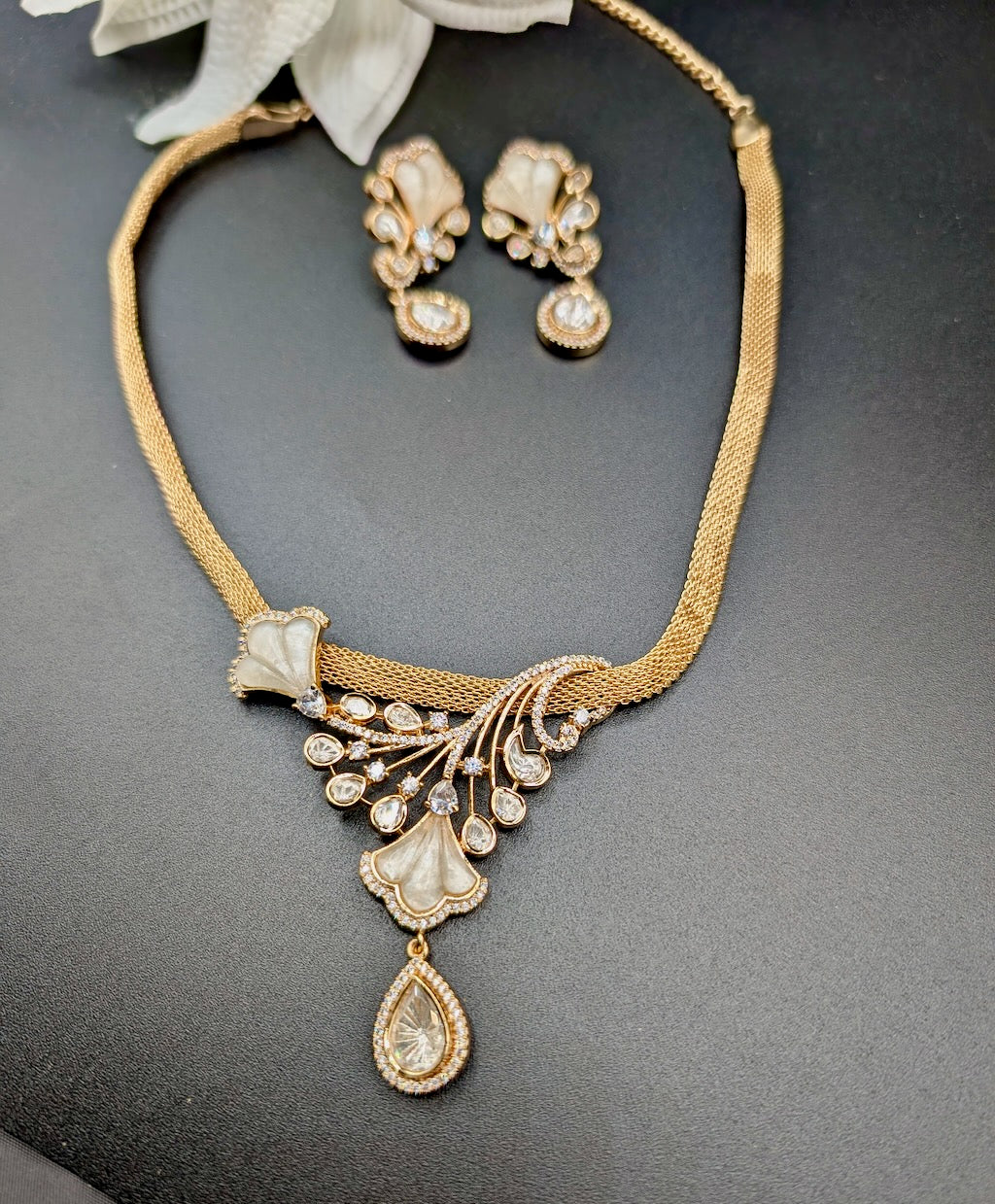 Gold necklace and earrings set on a dark surface